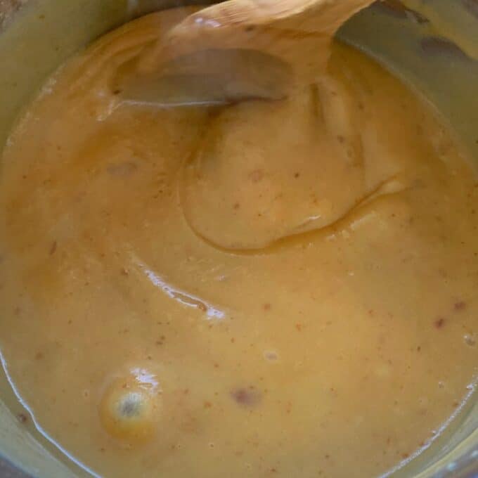 Condenced milk gently boiling to make caramal in a small pot.