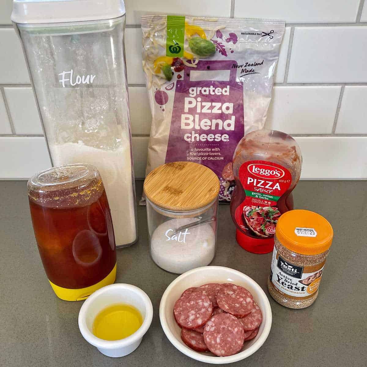 The ingredients to make a deep skillet pepperoni pizza on a grey bench top