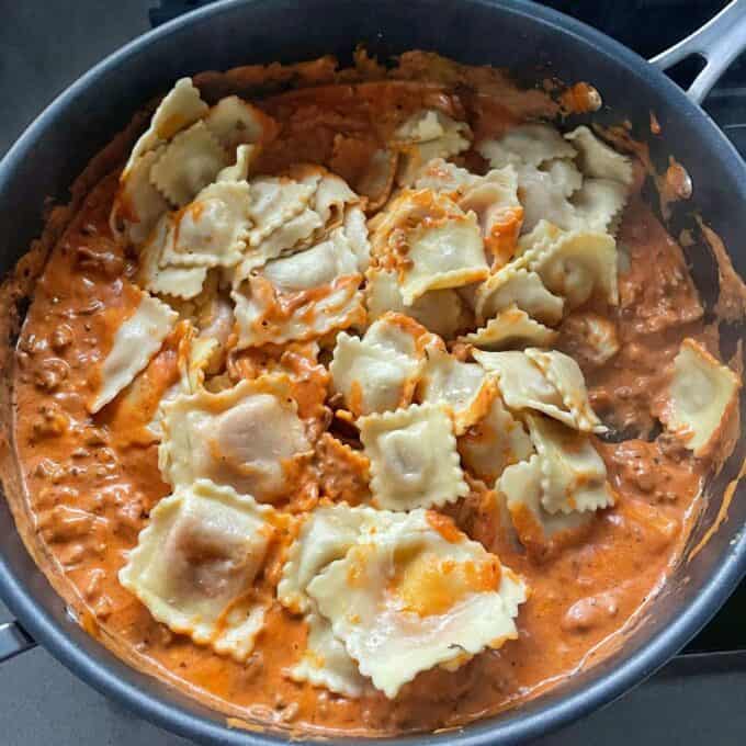 Cooked Tortelini being added to the mince mixture for Baked Mince Tortelini in a medium sized frypan.