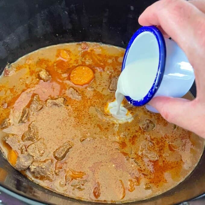 Combined cornflour and water being added to the curry to help thicken the sauce mixture.