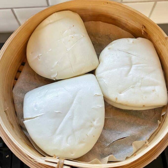 Bao buns placed inside a lined wooden steaming basket.