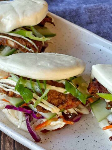 A close up of one Crispy Chicken Bao Bun so that you can see the chicken and salad filling.