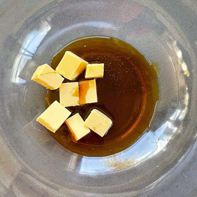 Cubed pieces of butter and golden syrup in a glass bowl.