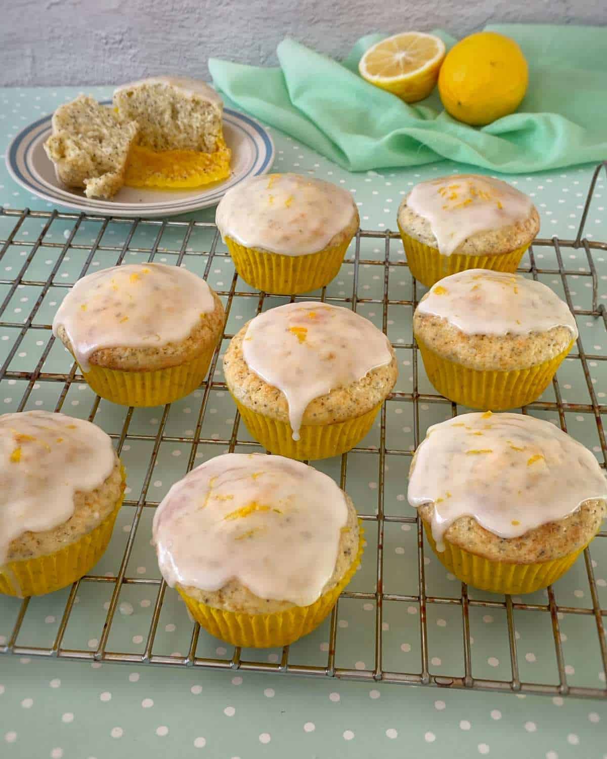 A secection of iced lemon poppyseed muffins on a baking rack.