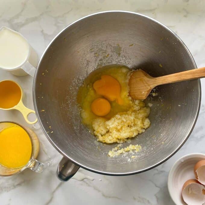 Sugar and lemon mix in a cake mixing bowl with two eggs being added.