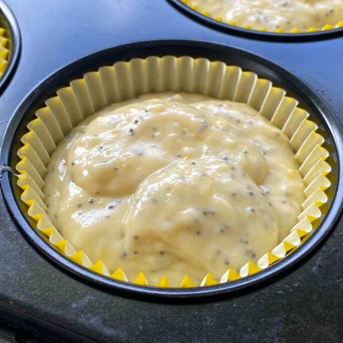 A close up of the lemon poppyseed filling in a yellow muffin case inside a muffin tin.