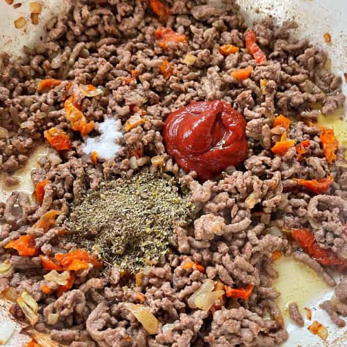 Mince, diced onion, herbs, sundreid tomatoes,tomato paste and sugar frying in a round ceramic dish.