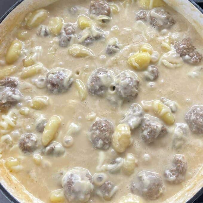 All of the ingredients for one pot creamy meatablls and gnocchi simmering in a ceramic dish.