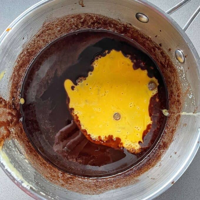 Melted chocolate with a whisked egg added to it in a large pot.