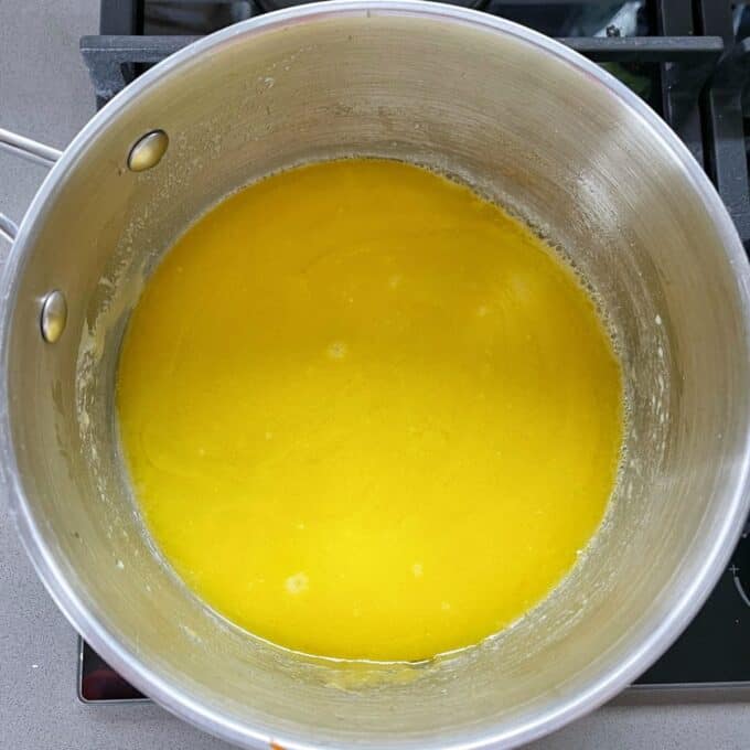 A large saucepan filled with melted butter on the stove top.