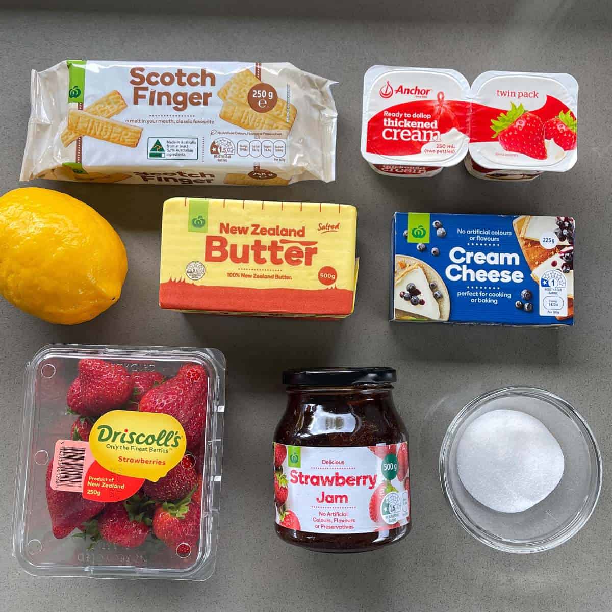 The ingredients for strawberry cheesecake slice on a grey bench.