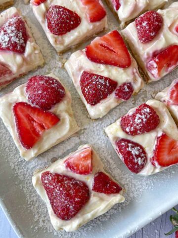 A close up of pieces of strawberry cheesecake slice on a white plate.