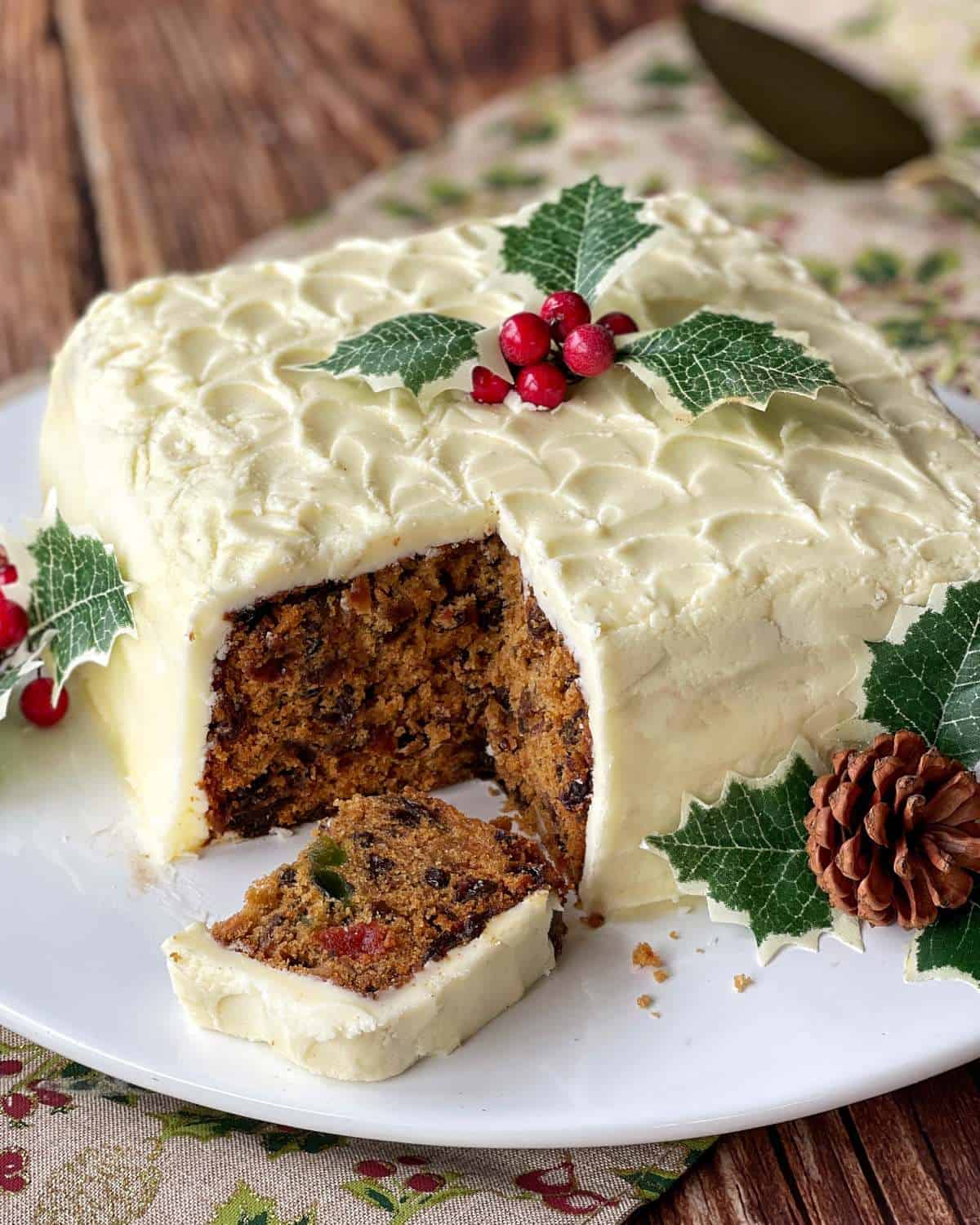 A close up a traditional fruit cake with a piece cut from the corner.