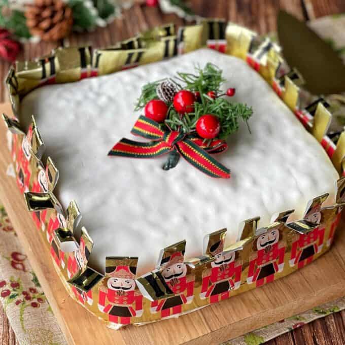 A close up of an iced Christmas cake, decorated with some Christmas mistletoe