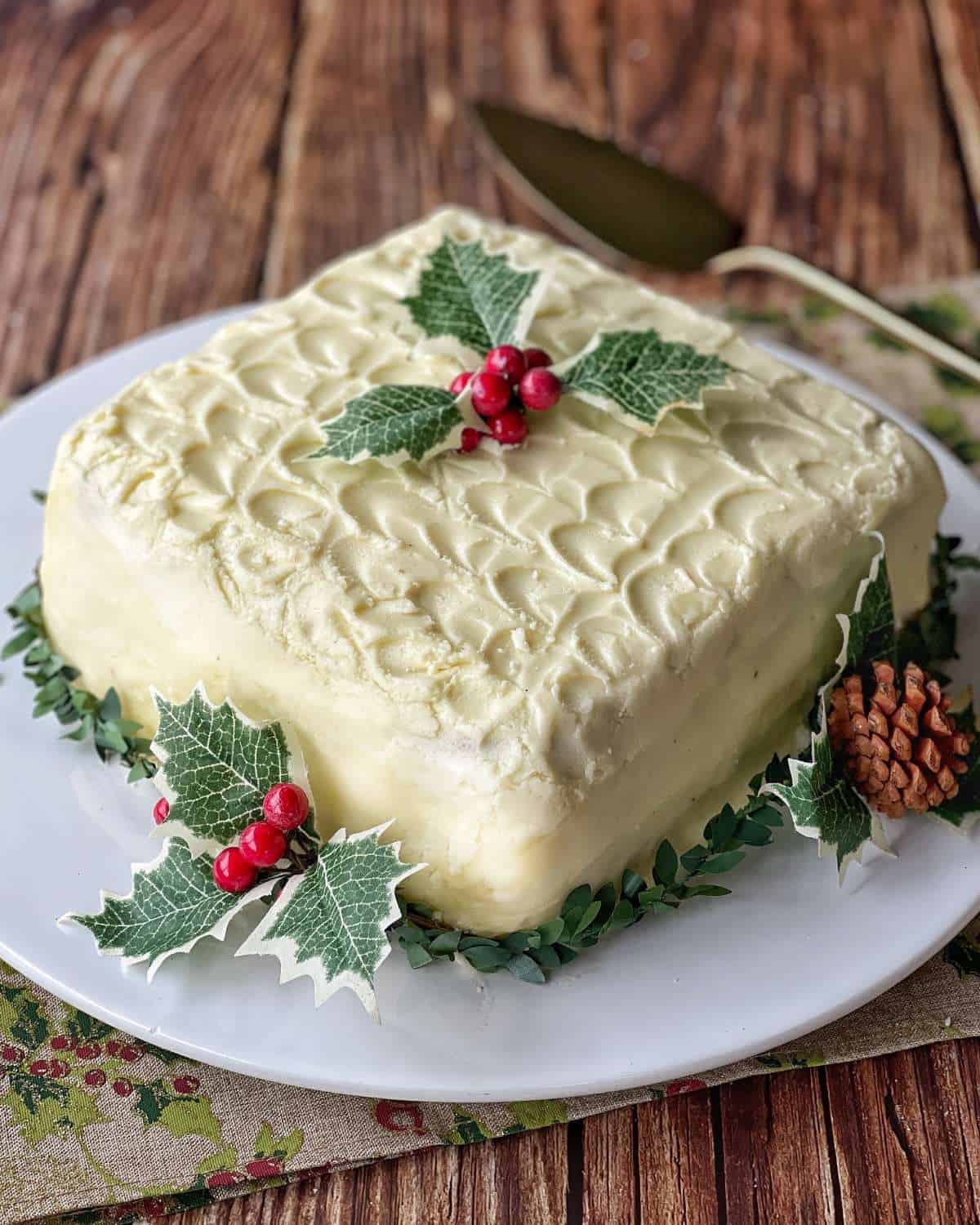 A close up of an iced Christmas cake, decorated with some Christmas mistletoe