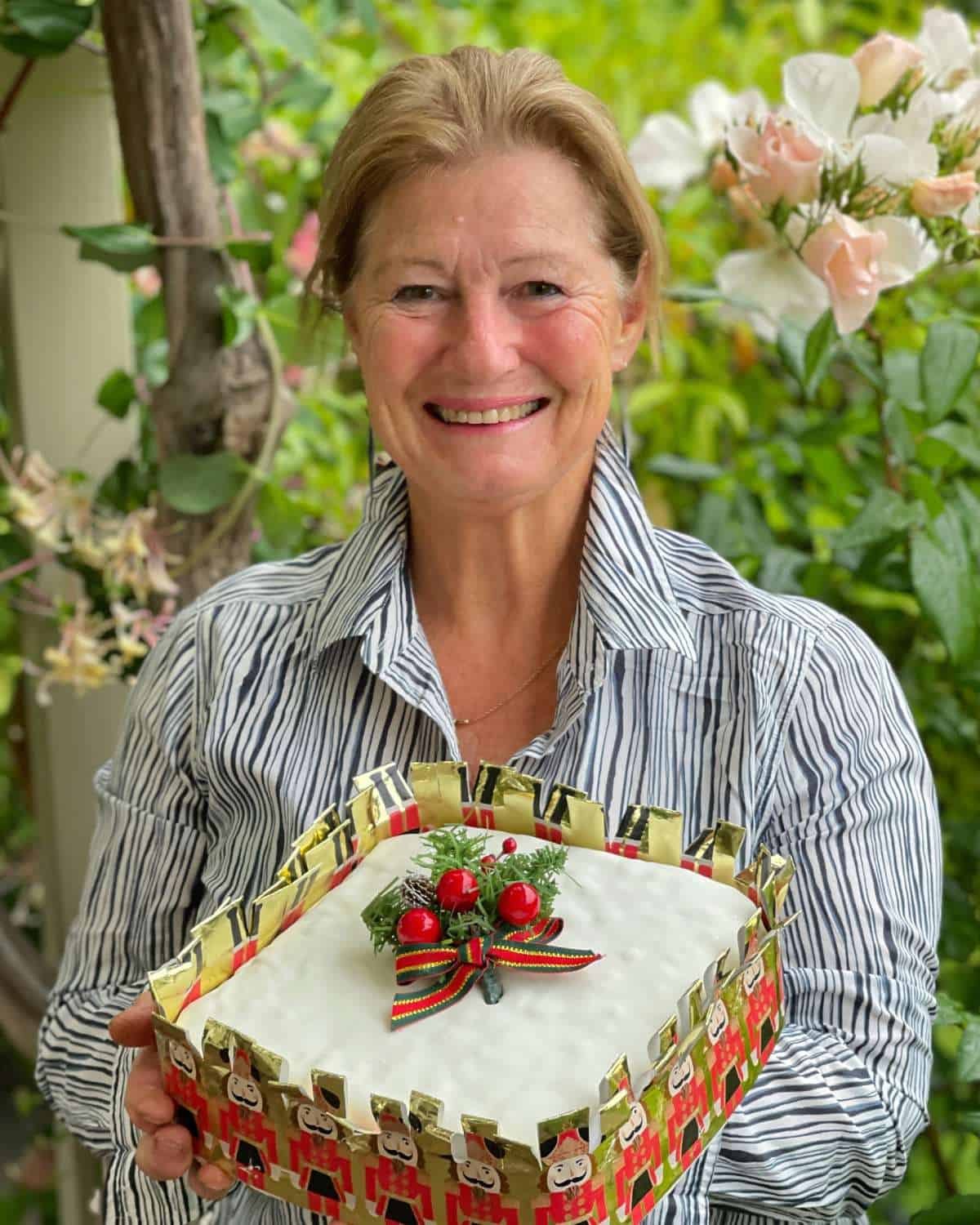 A woman smiling holding a Christmas cake