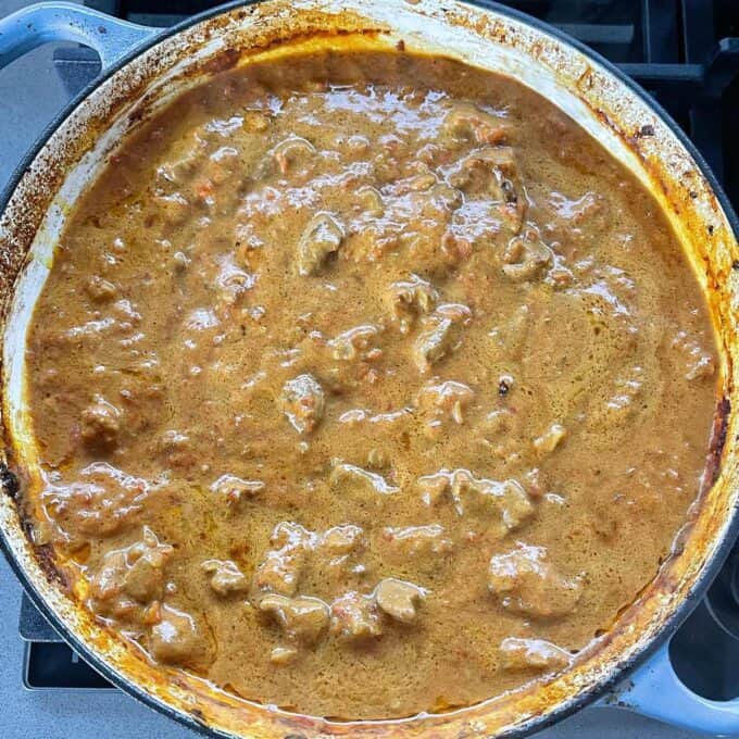 Lamb Sagg curry mixture simmering in a round ceramic dish