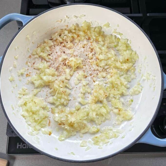 Garlic and onion frying in a round ceramic dish over a medium heat