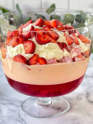 A completed Strawberry Lamington Triffle in a glass triffle dish showing the different strawberry layers.
