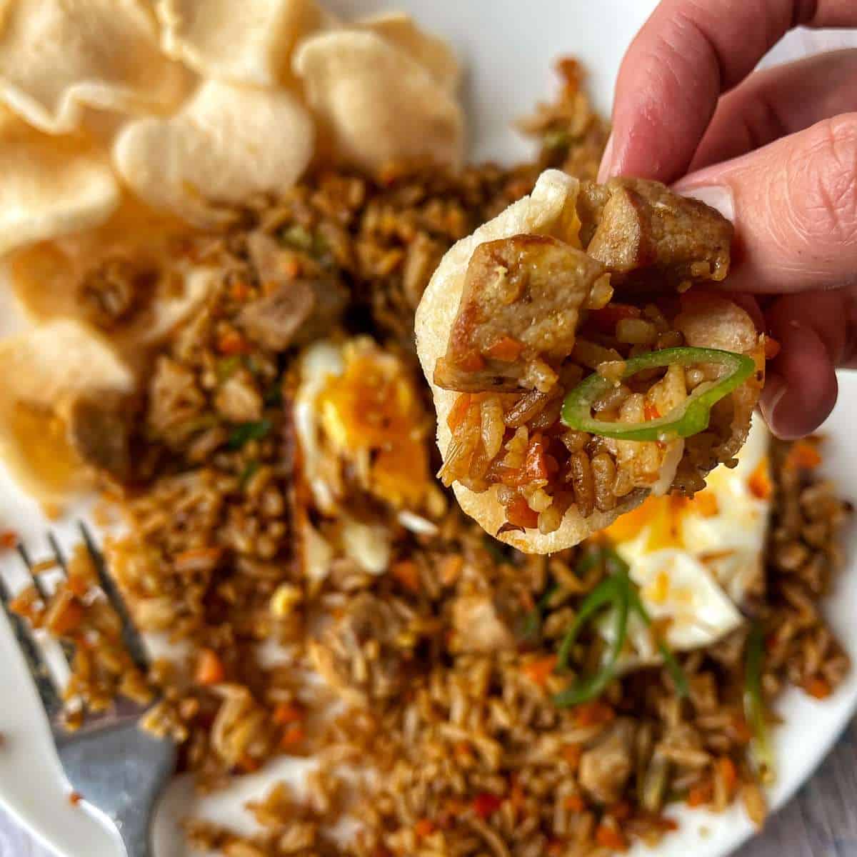 A close up of a prawn cracker with Nasi Goreng scooped up inside it.