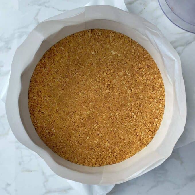 The whizzed superwine and butter mixture spreadout in a lined round baking tin to form the bottom of the cheesecake.