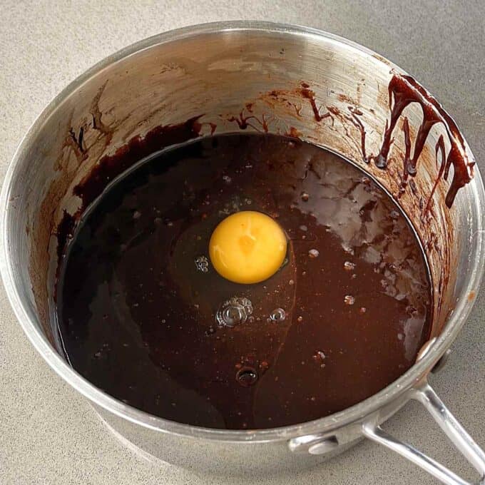 Chocolate paste in a saucepan with an egg cracked in.