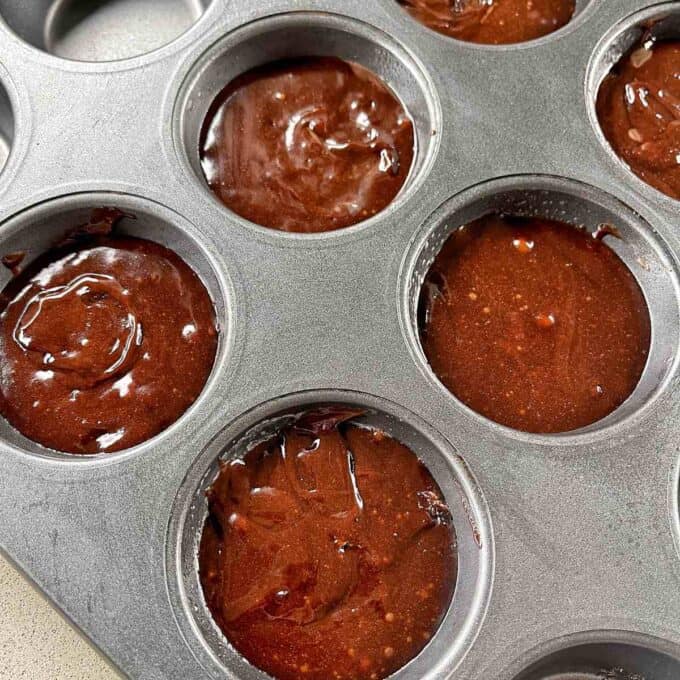 Uncooked brownie mixture in muffin tins.