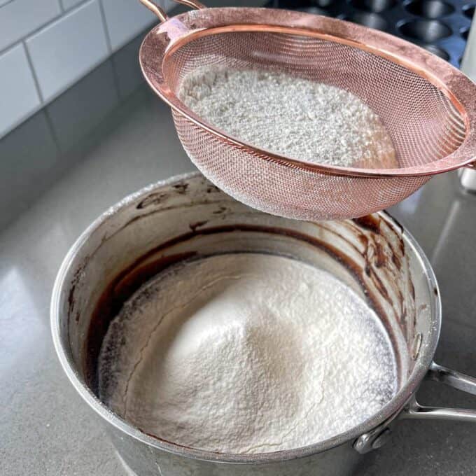 Flour being sifted into a saucepan.