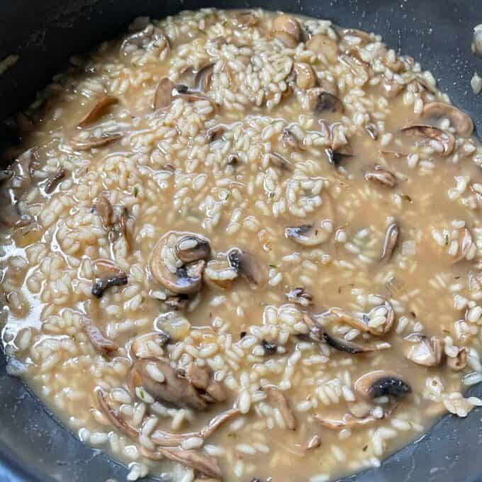 All lof the componets of mushroom risotto gently simmering in a frypan.