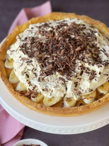 An assembled Banoffee Pie sitting on a white cake stand.