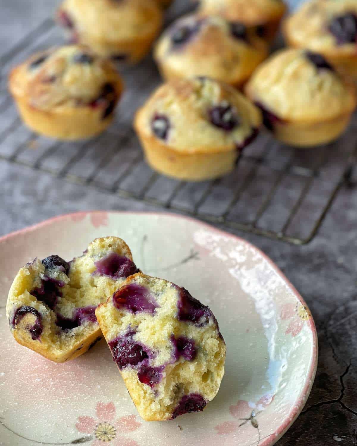 A cooked and split open blueberry muffin on a small plate.