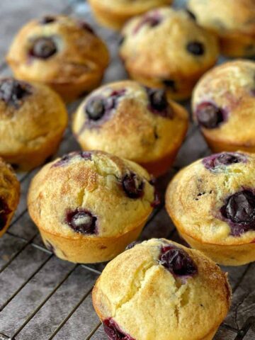 A selection of cooked blueberry muffins on a cooling rack.