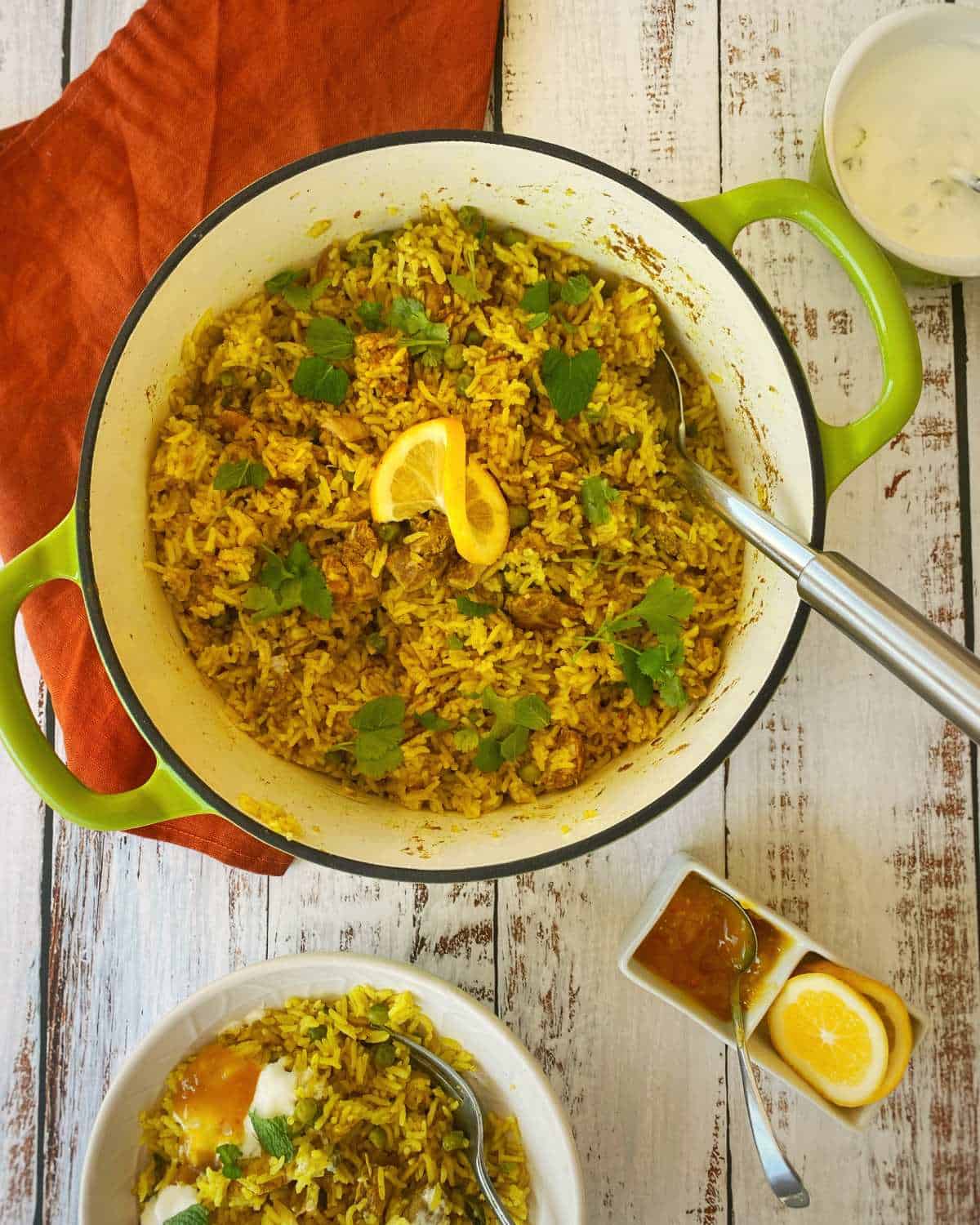 Cooked Chicken Biryani served in a round ceramic dish with a slice of lemon and scattered coriander on the top.