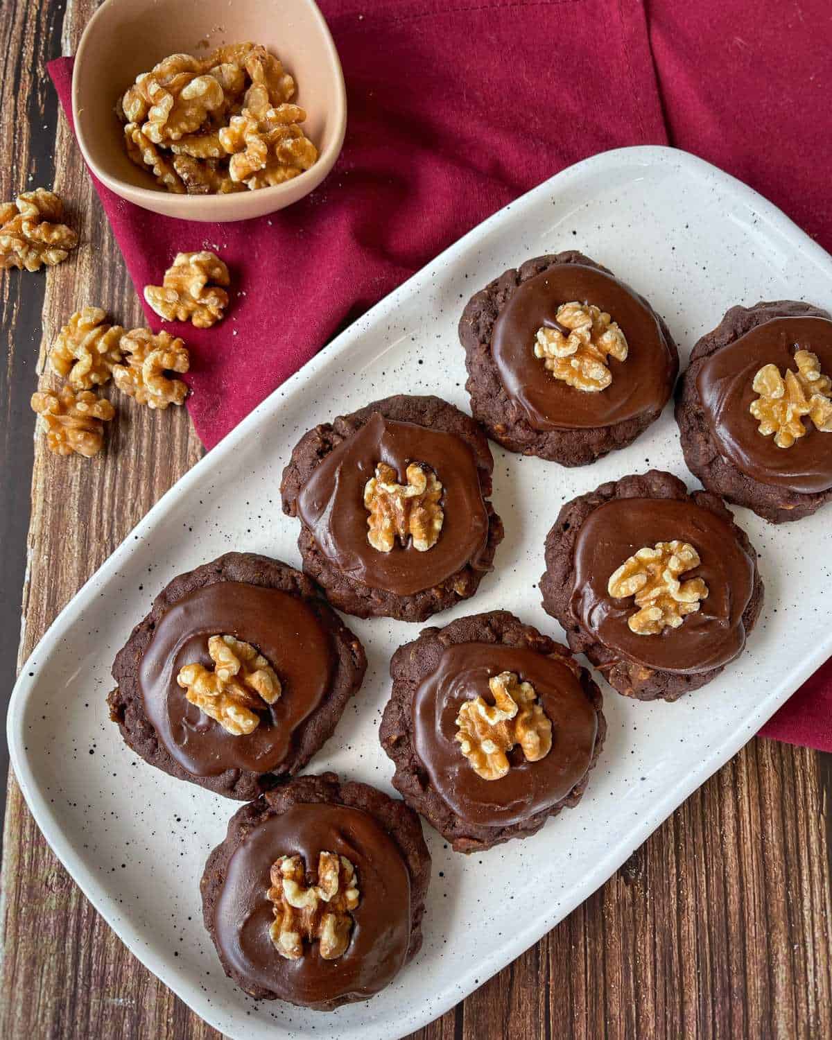 A selection of iced chocolate cornflake biscuits on a white plate on a wooden table.