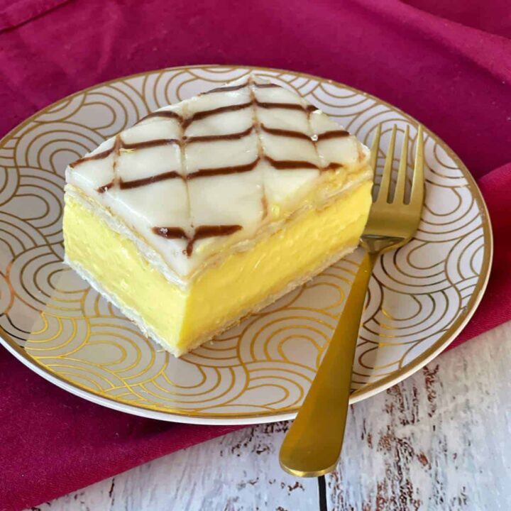 One custard square served on a small plate with a gold fork.