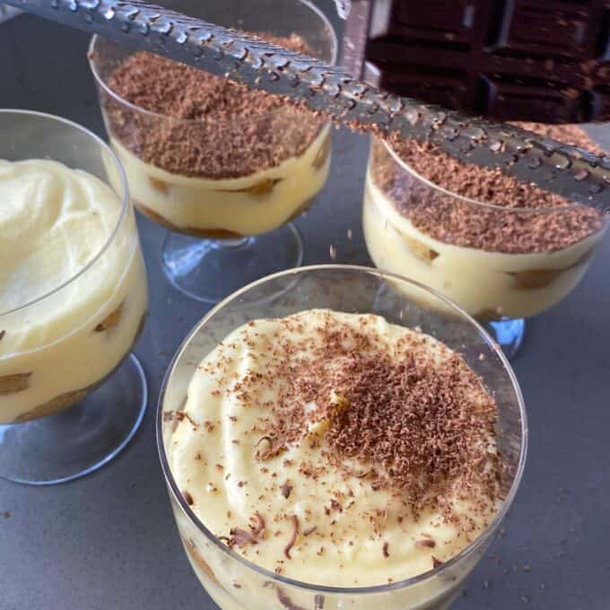 Chocolate being grated over the individual tiramisu's