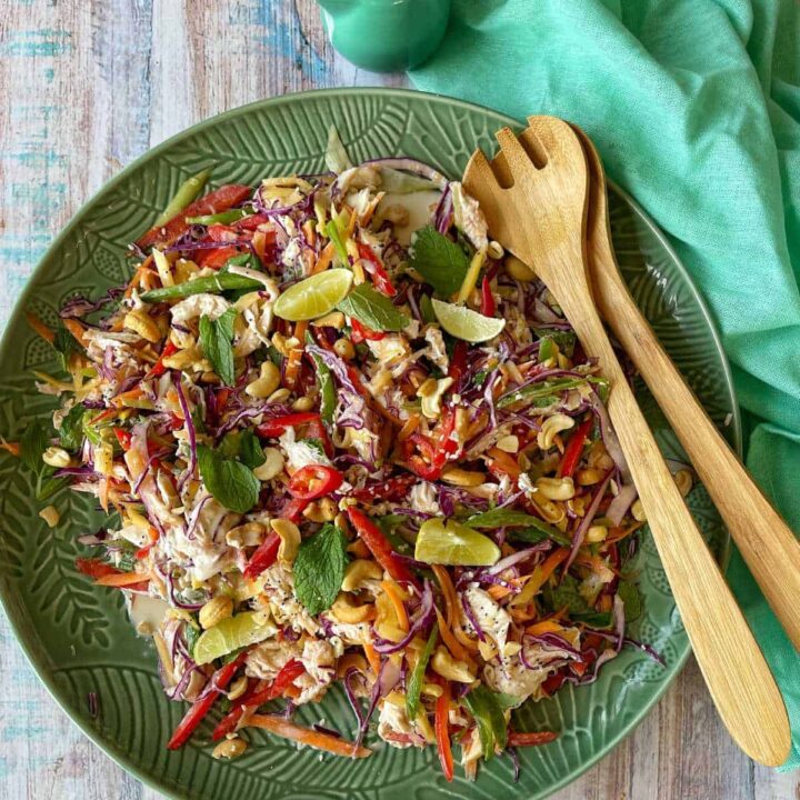 A birdseye view of Thai Style Chicken Slaw served on a round platter with wooden serving sppons.