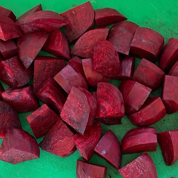 Diced peices of beetroot on a green chopping board.