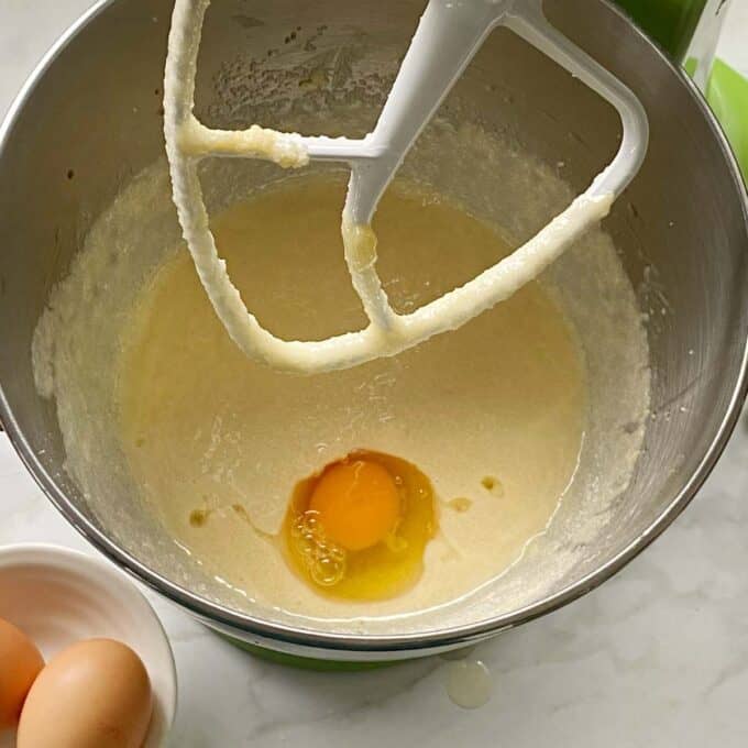 Cake batter in a mixing bowl. One egg has been added but not mixed through.