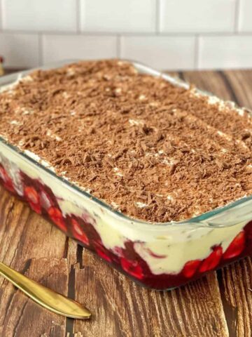 A close up of an assembled trifle in a glass dish showing the different layers.