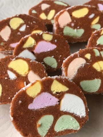 Slices of chocolate dessert with colorful marshmallow pieces, known as lolly cake, are arranged on a plate.
