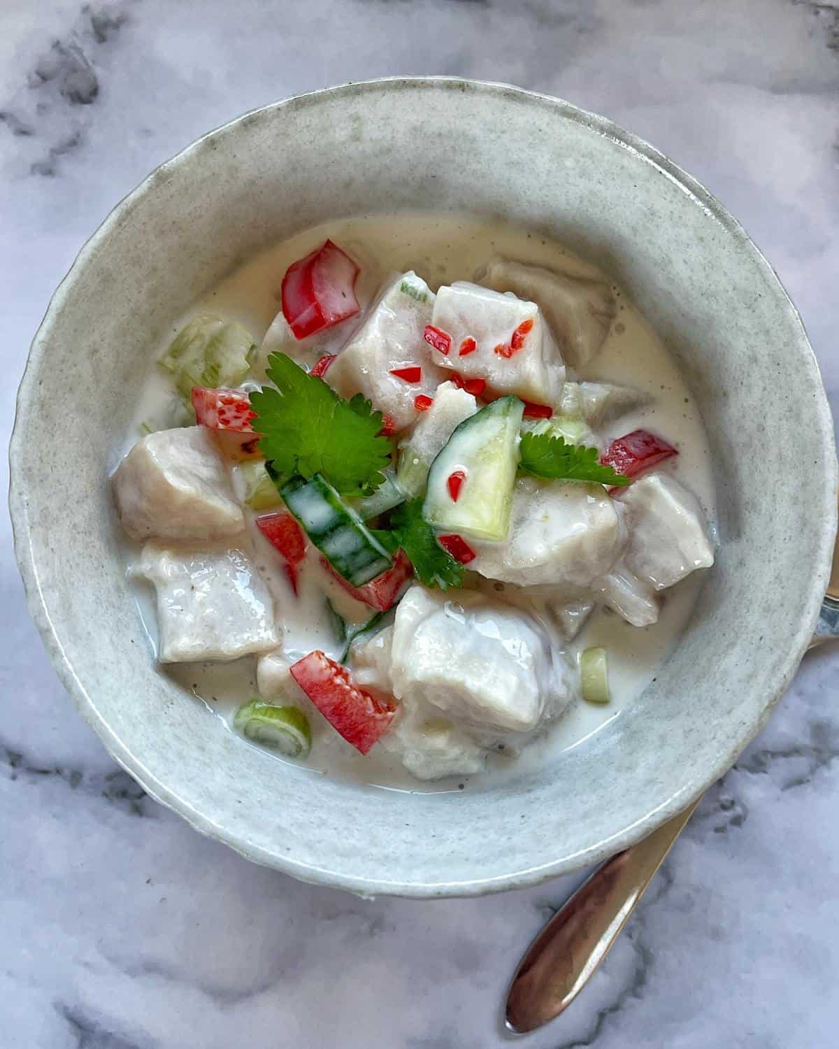 A small bowl of ceviche served with scattered parsley and a few chilli flakes