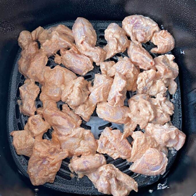 Uncooked marinated chicken pieces in a air fryer