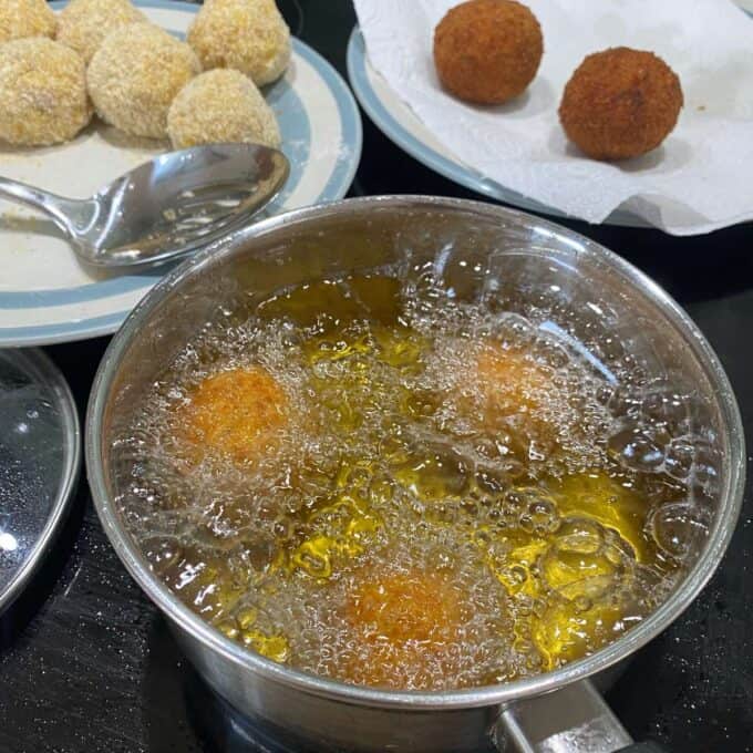 Arancini Balls deep frying in a pot of hot oil