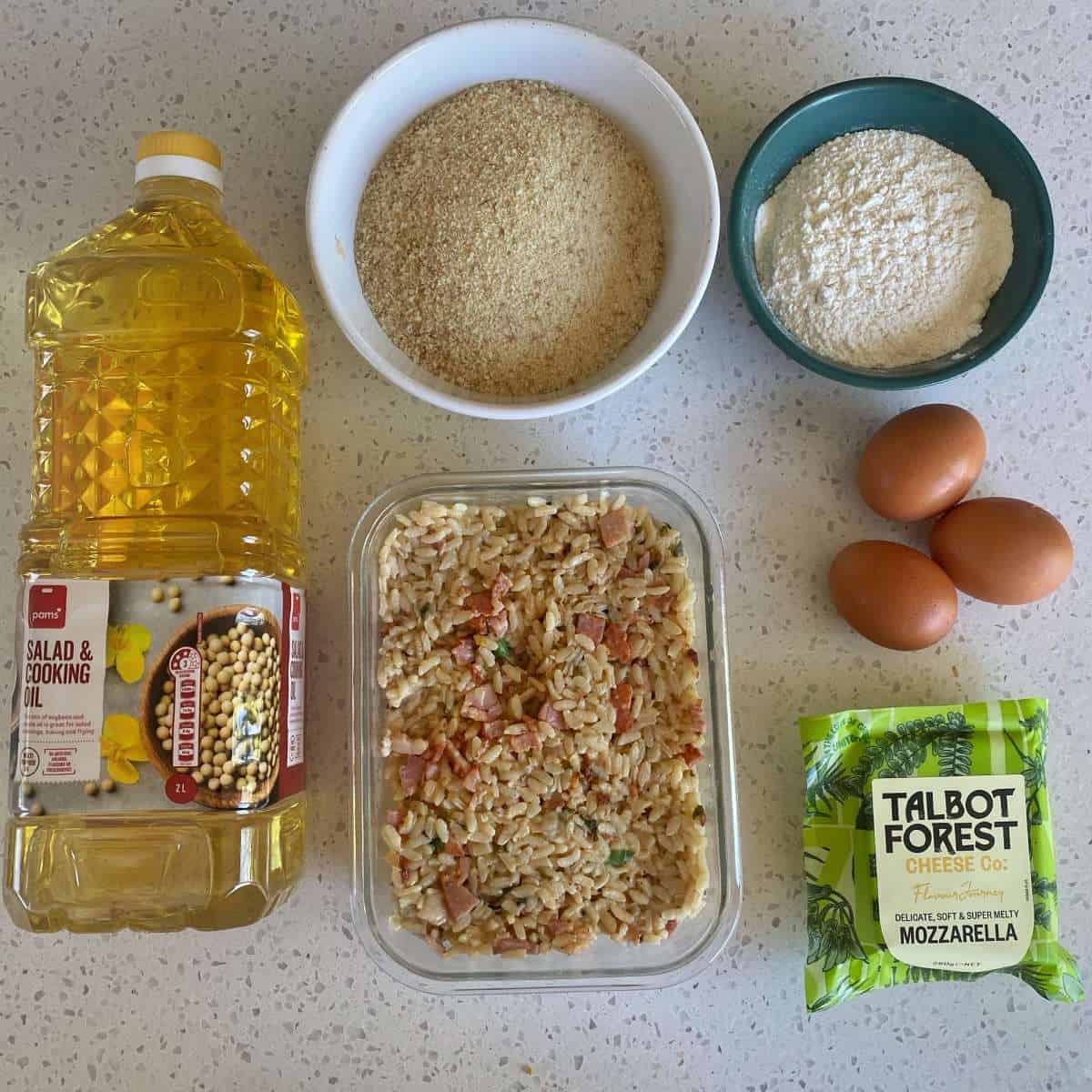 The ingredients to make arancini balls on a marble bench top