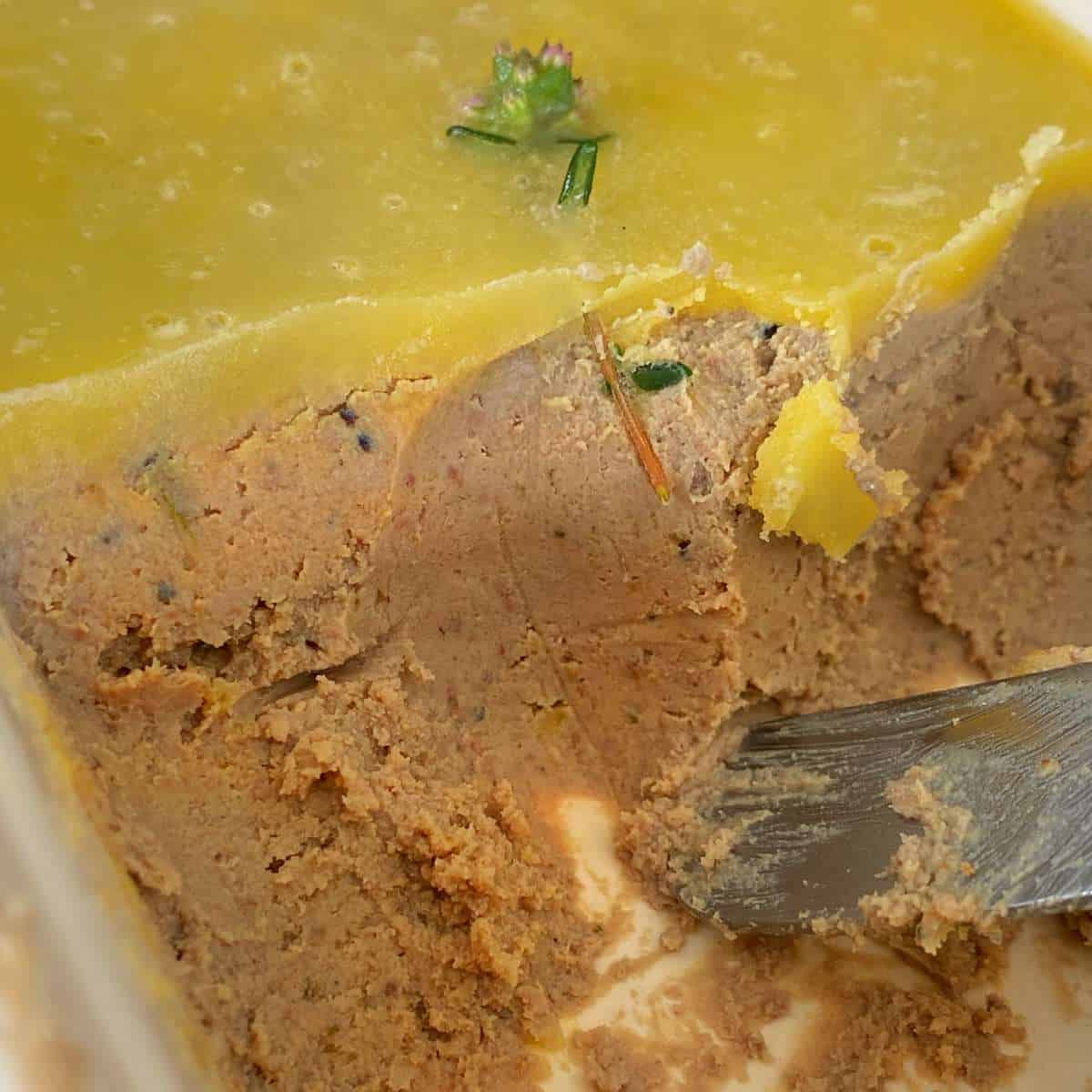 A close of shot of chicken liver pate being cut with a butter knife