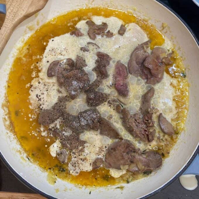 Chicken livers cooking in butter, cream and spices in a round ceramic dish