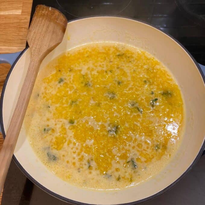 Butter, onion, garlic and herbs frying in a round ceramic dish