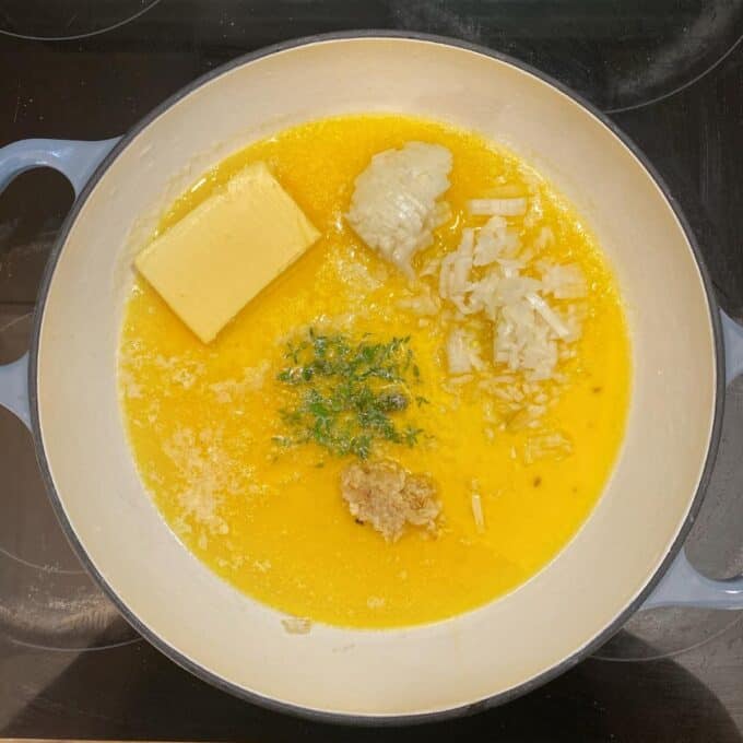 Butter, onion, garlic and herbs frying in a round ceramic dish