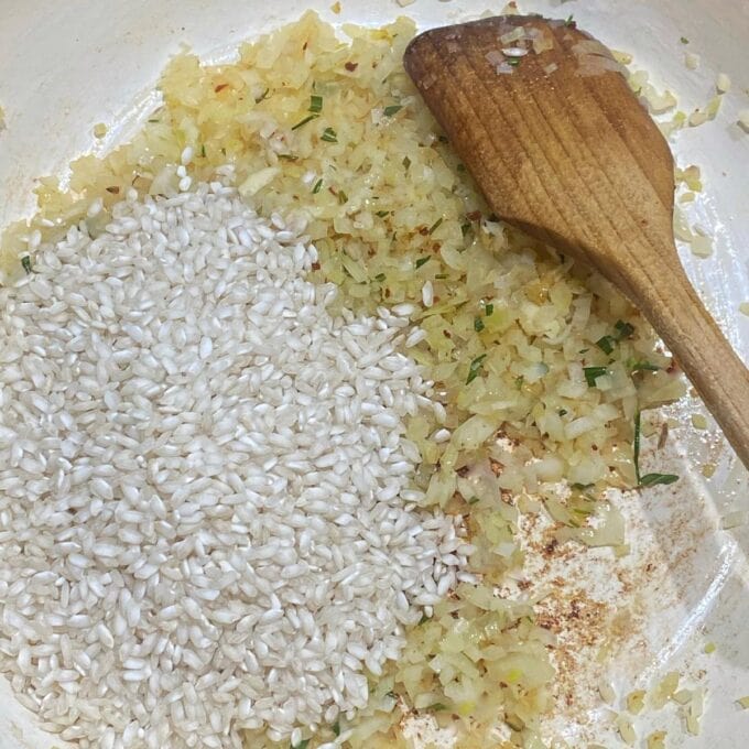 Risotto rice being added to fried garlic and onion